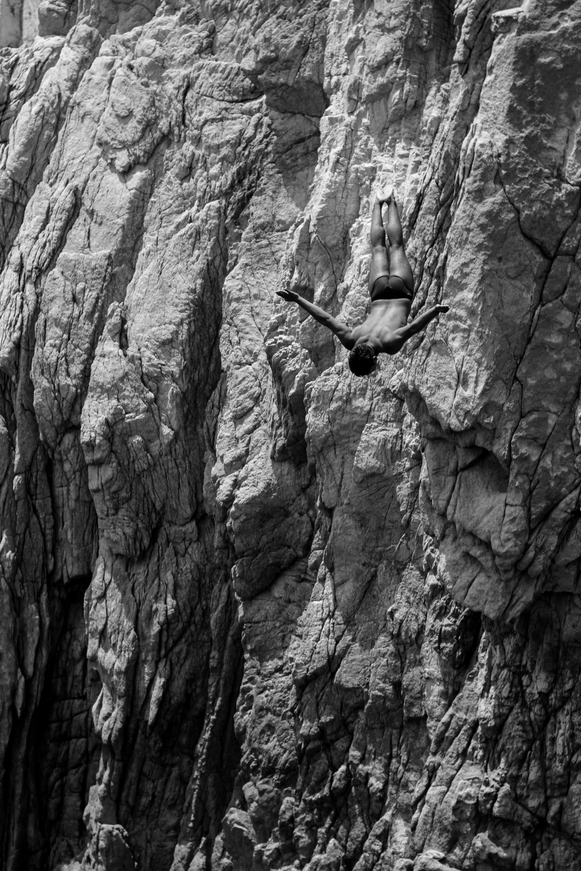 A person climbing a rock wall with a harness and safety gear.