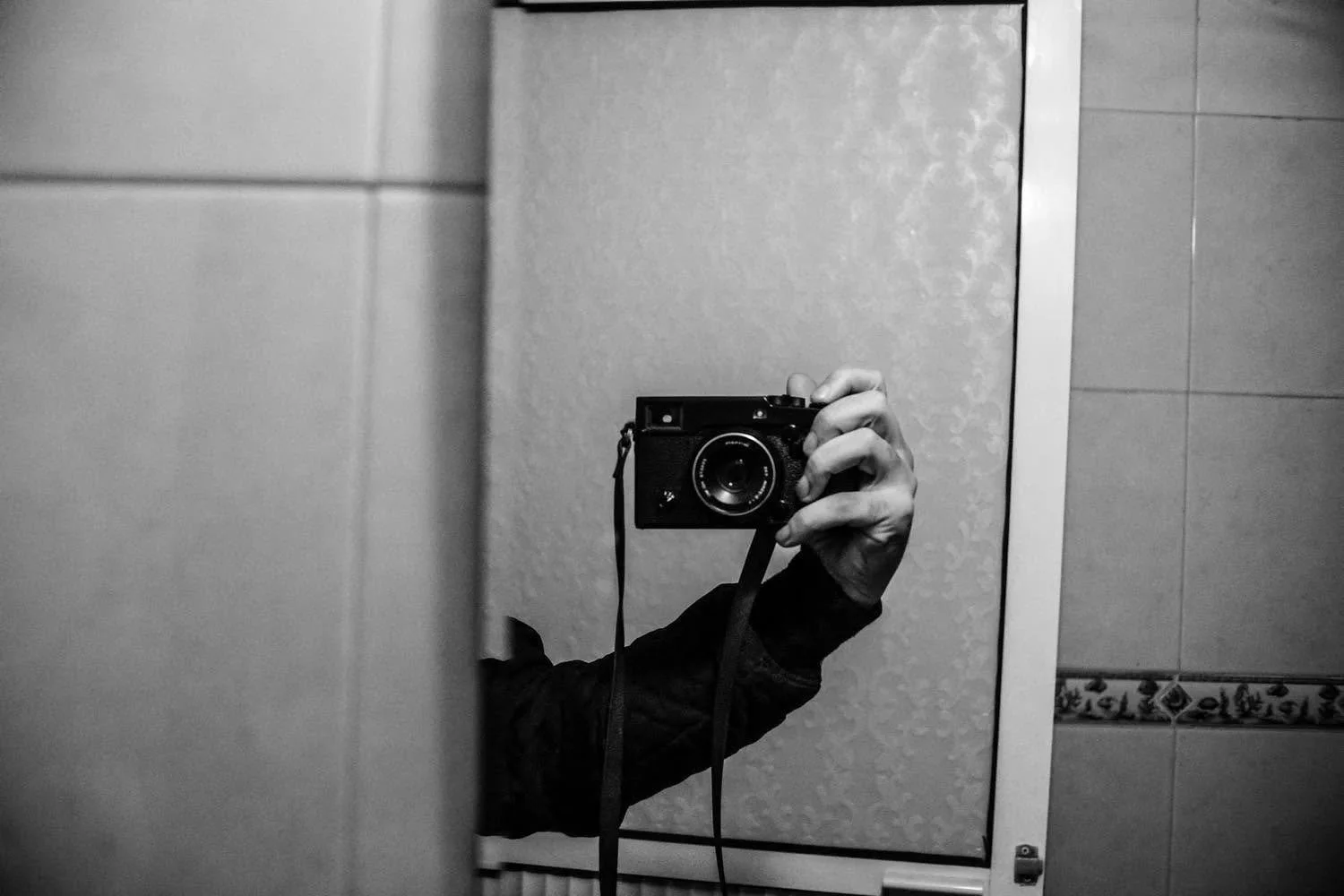 Self portrait of photographer Alex Coghe holding a camera in front of a mirror