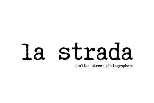 Logo with the words 'la strada' and 'italian street photographers' on a white background.
