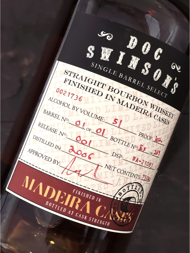 A bottle of Doc Swinson's single barrel bourbon whiskey with detailed labeling including alcohol volume, proof, barrel number, and release date.