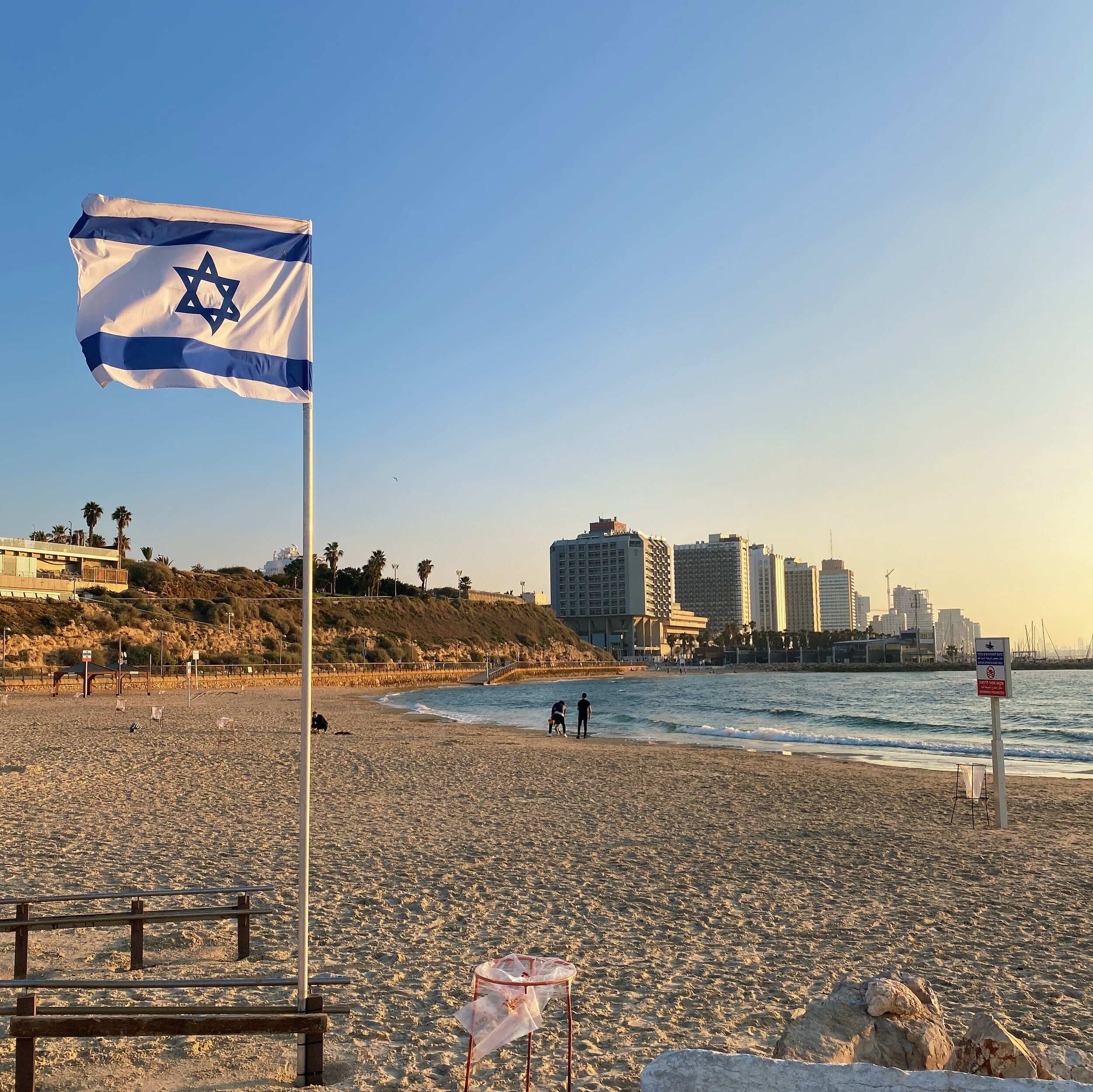 Israeli flag flying on the beach with the Tel Aviv skyline