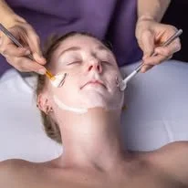a creamy moisture mask is applied with fan brushes for a sensory experience during a comforting All Aglow Spa facial