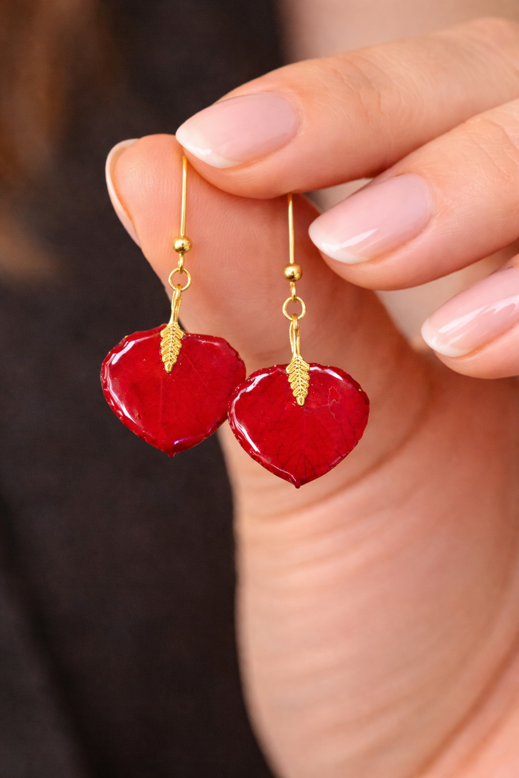 red resin earrings in womans hand.png