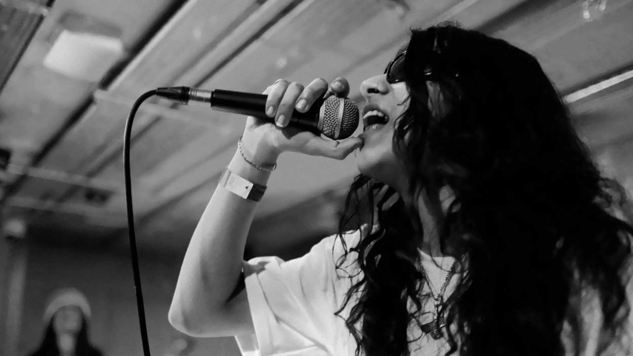 Black and white image of a person singing into a microphone on stage.