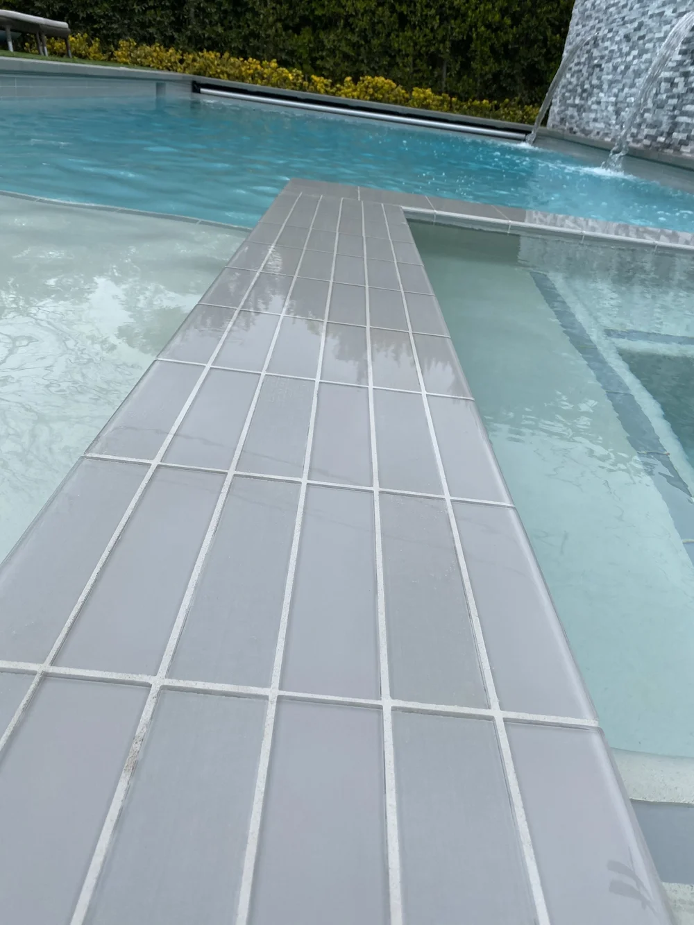 Close-up of a straight gray-tiled divider between a pale spa interior and the main pool.