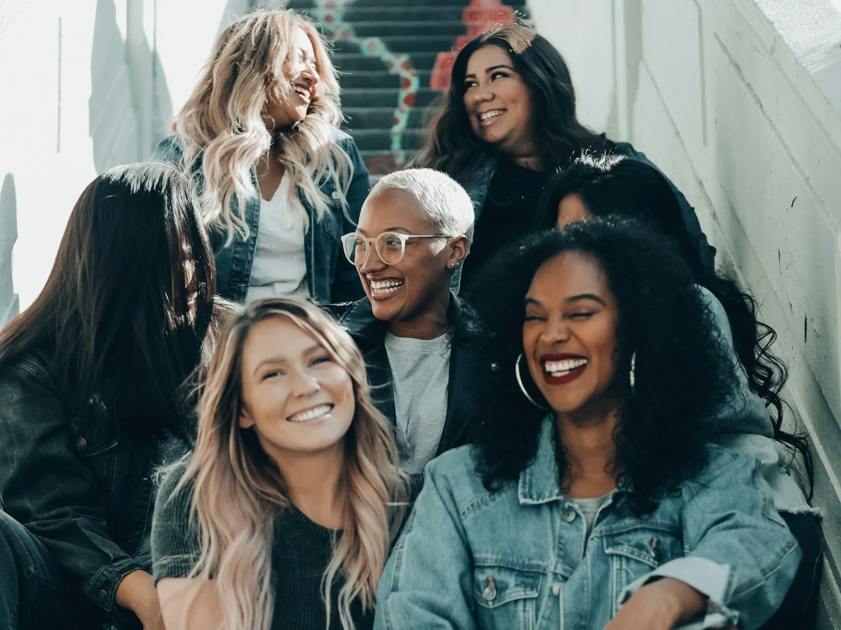 Group of diverse women smiling and laughing on a staircase.