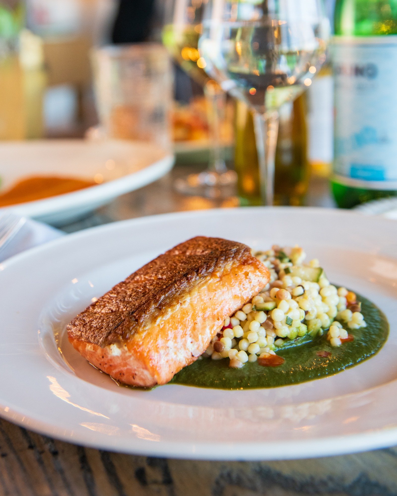 Make plans to join us this week! Try one of our popular seafood dishes like this crispy skin salmon with vibrant summer fregola, and sweet herb puree. #letseat