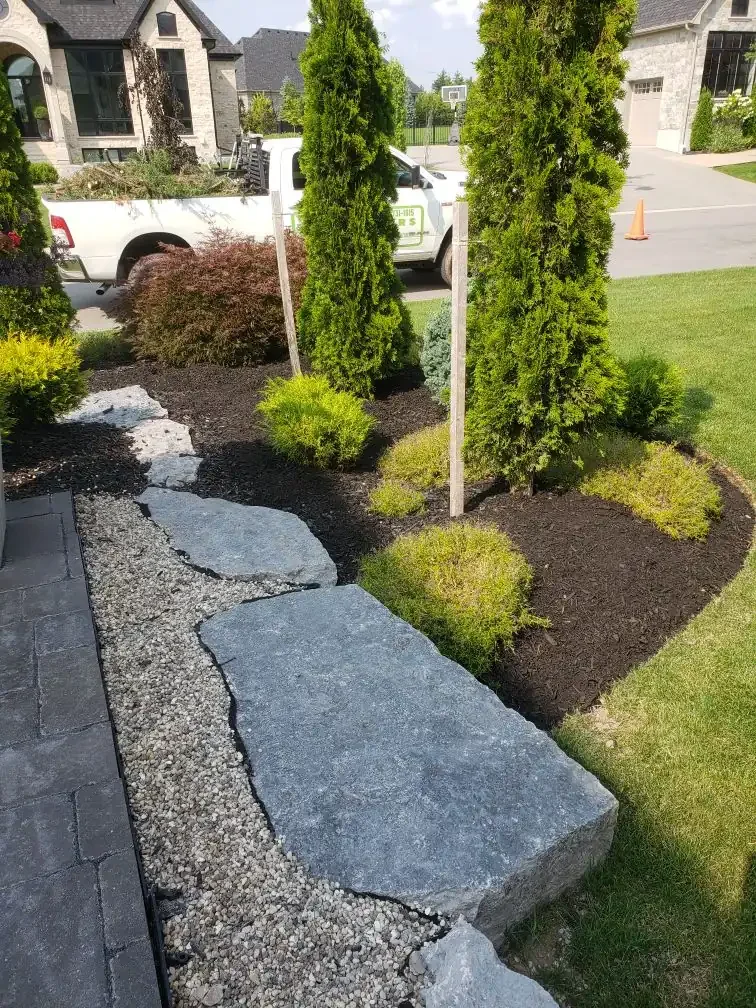 Professional garden designed with plants, trees, mulch, armour stone, and ornamental stones in Guelph, Ontario