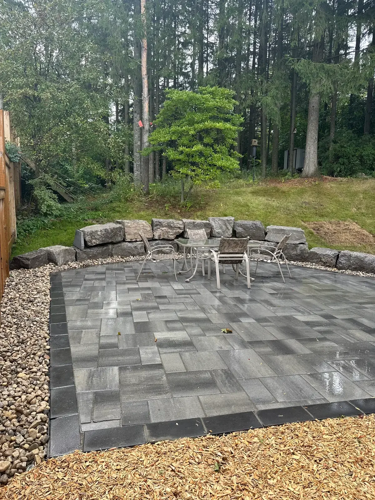 Backyard interlock paver patio installed with an armour stone retaining wall in Cambridge, Ontario