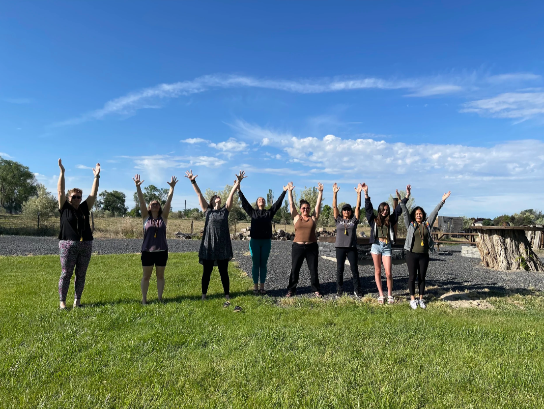 Women standing outside with arms extended
