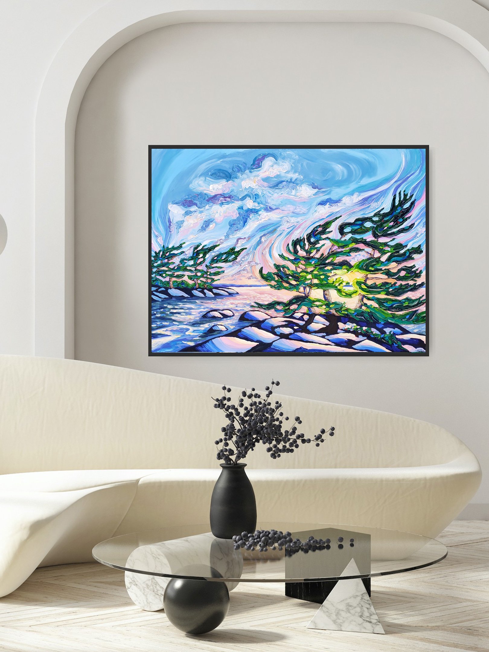 Abstract landscape painting of a windy shoreline with pine trees, rocks, water, and a colorful sky, hung on a white wall in a modern living room.