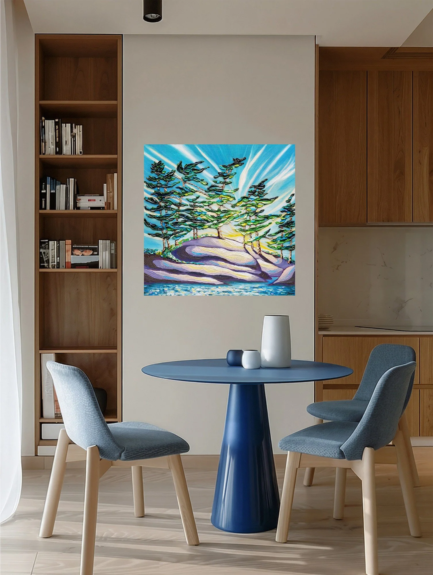 Landscape painting of windswept trees along the water under a beaming sun, styled in a modern interior with a table and chairs.