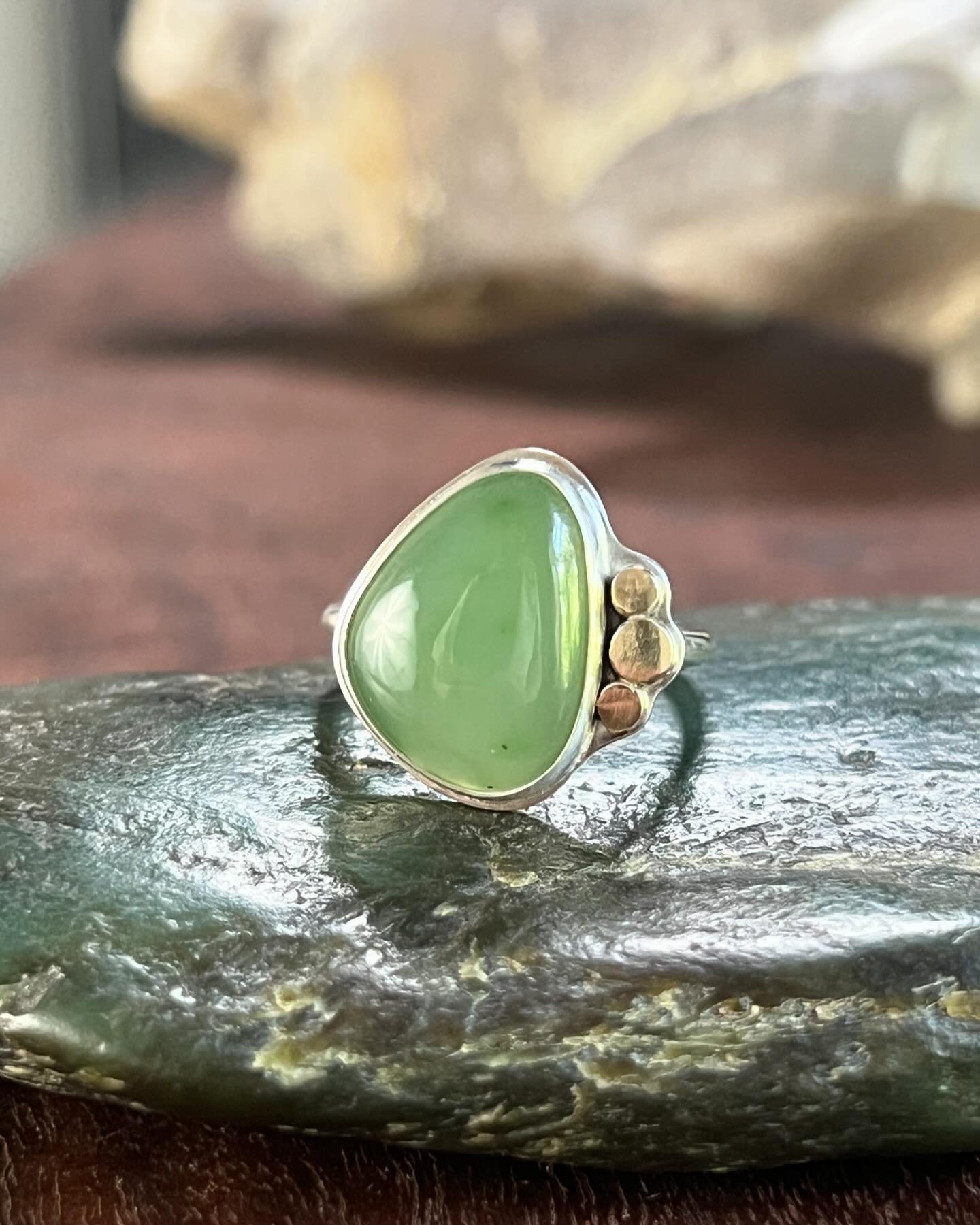 Presenting a size 6.5 sterling silver ring featuring a captivating Siberian green jade gemstone, encircled by fine gold details. This stunning creation embodies the tranquil allure of the jade, complemented by the elegant sterling silver band, making