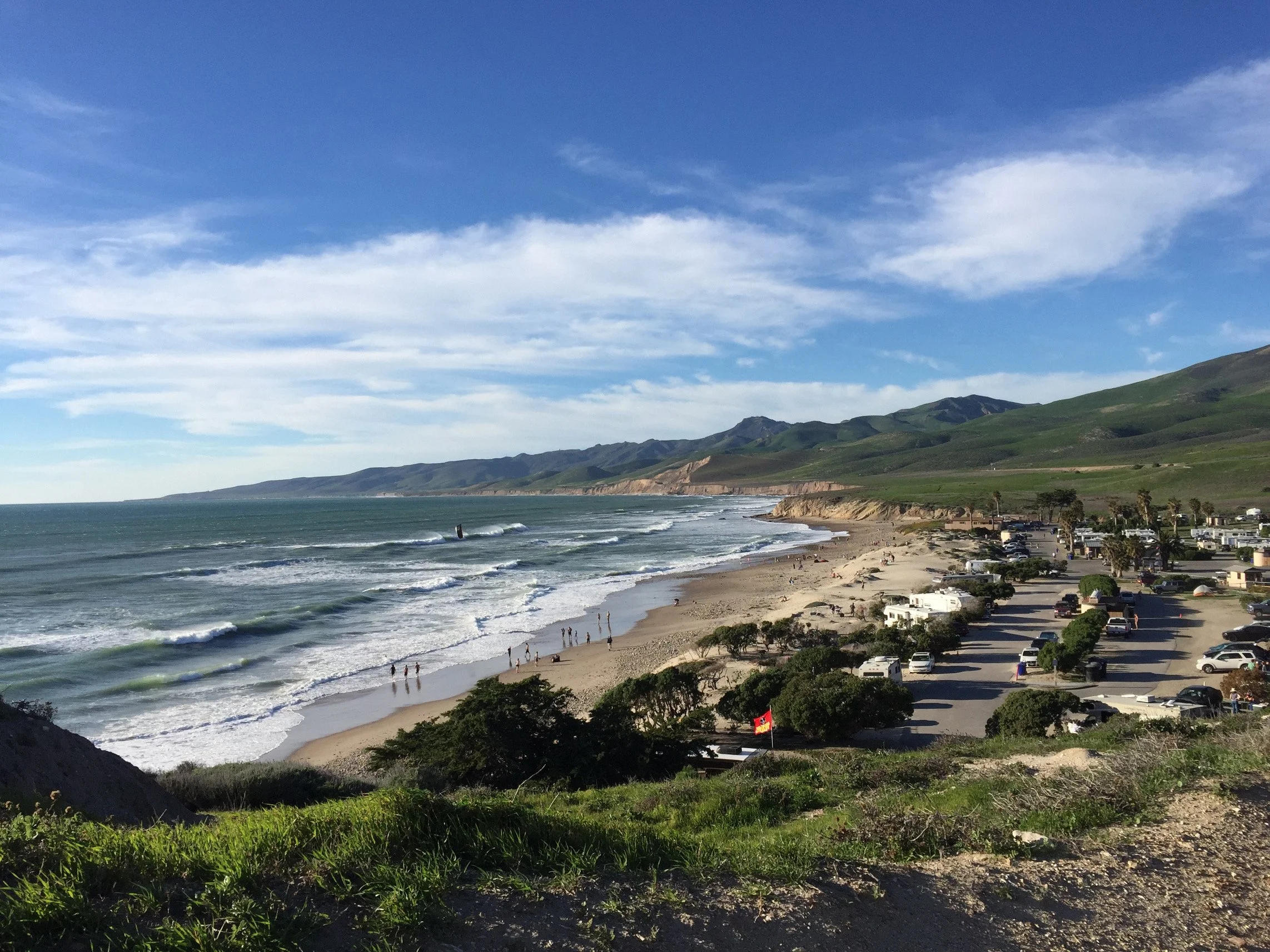 Sunset view of a beach with gentle waves and sandy shoreline.