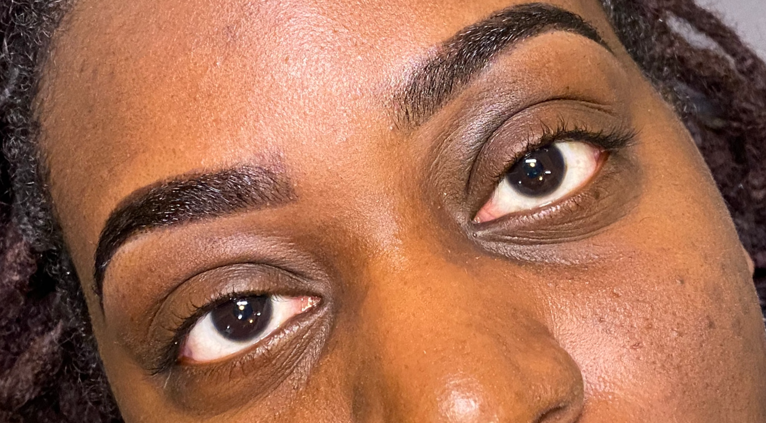 Close-up of a woman's face showing her eyes, eyebrows, and part of her nose.