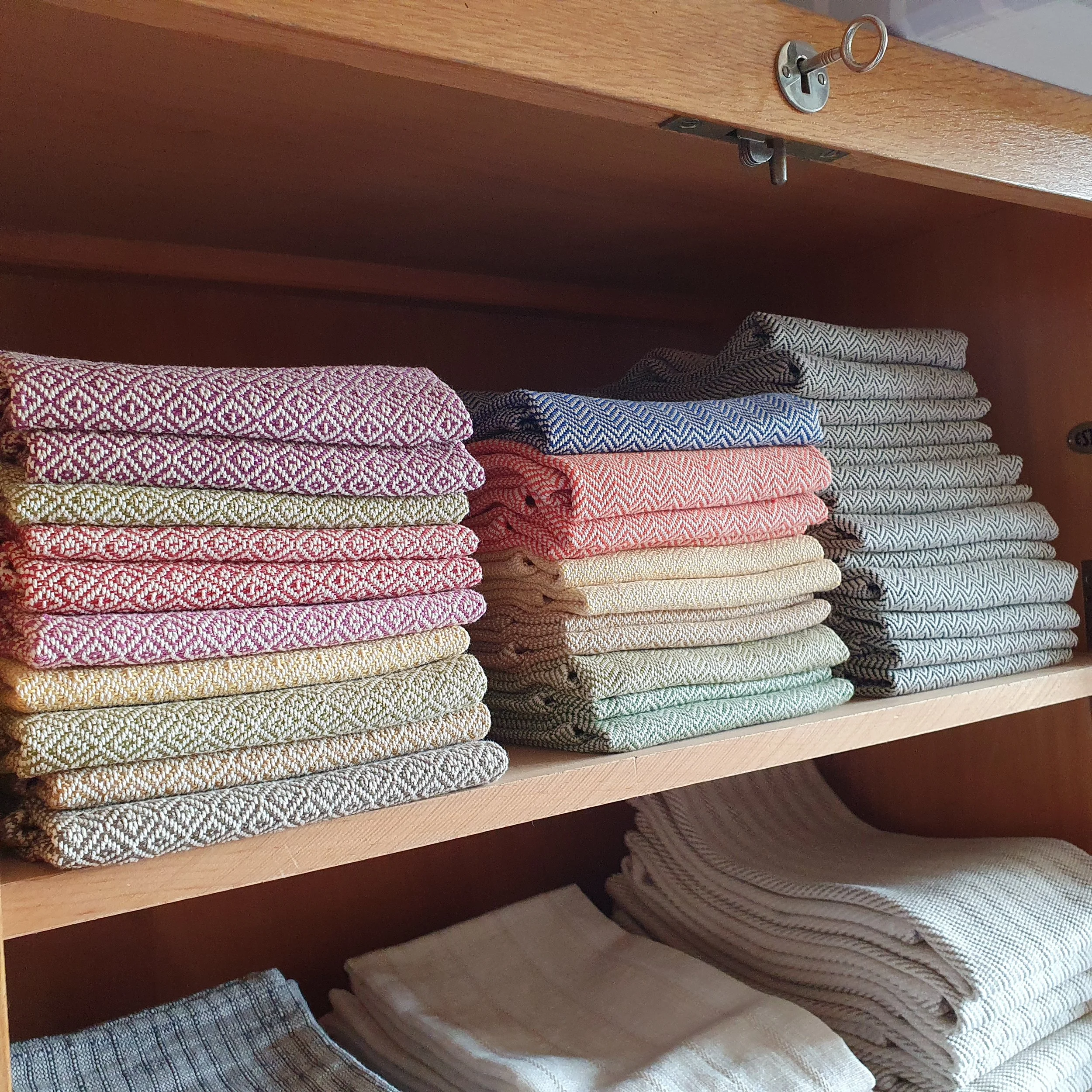 Tücher in verschiedenen Farben und Mustern auf einem Holzregal