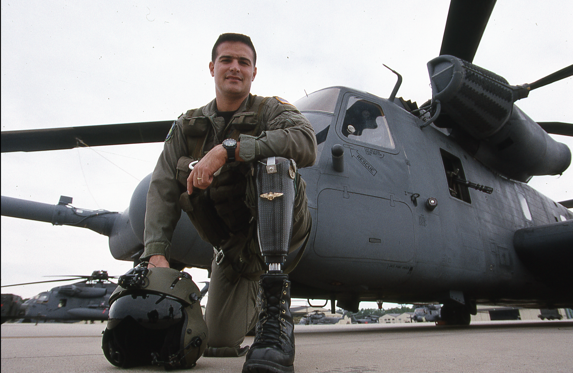 Legendary image of John Alvarez kneeling in front of his MH-53J Pave Low Special Ops helicopter with his prosthetic leg visible, featured in FOX 13 coverage of Walk, Run, Fly Again