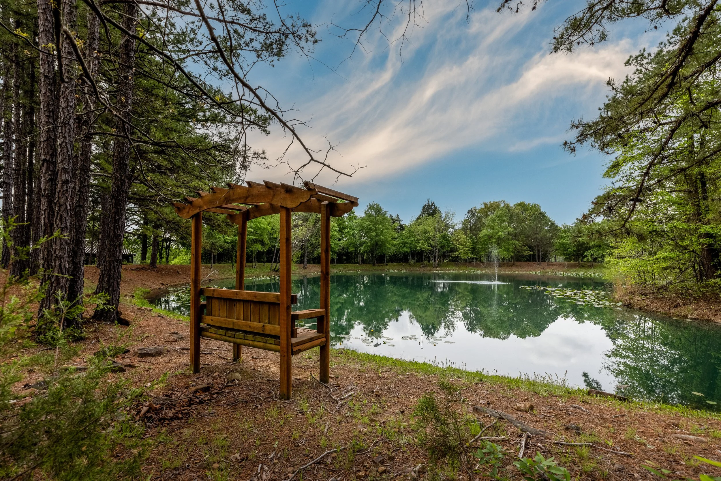 Wooded pond with a wooden bench at Timber Ridge Estates