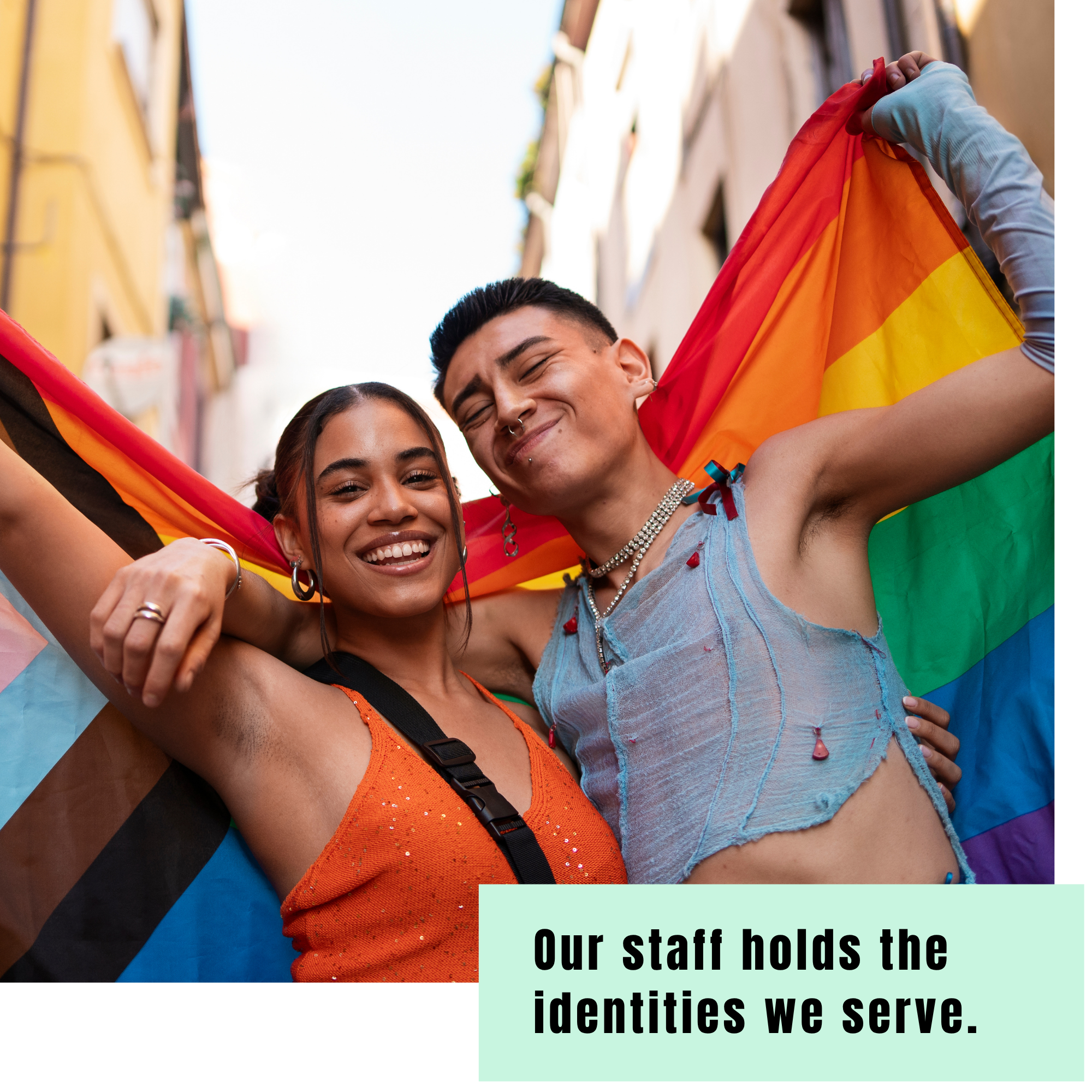 Two smiling people stand close together wrapped in Pride flags. A light teal text box reads, “Our staff holds the identities we serve.”