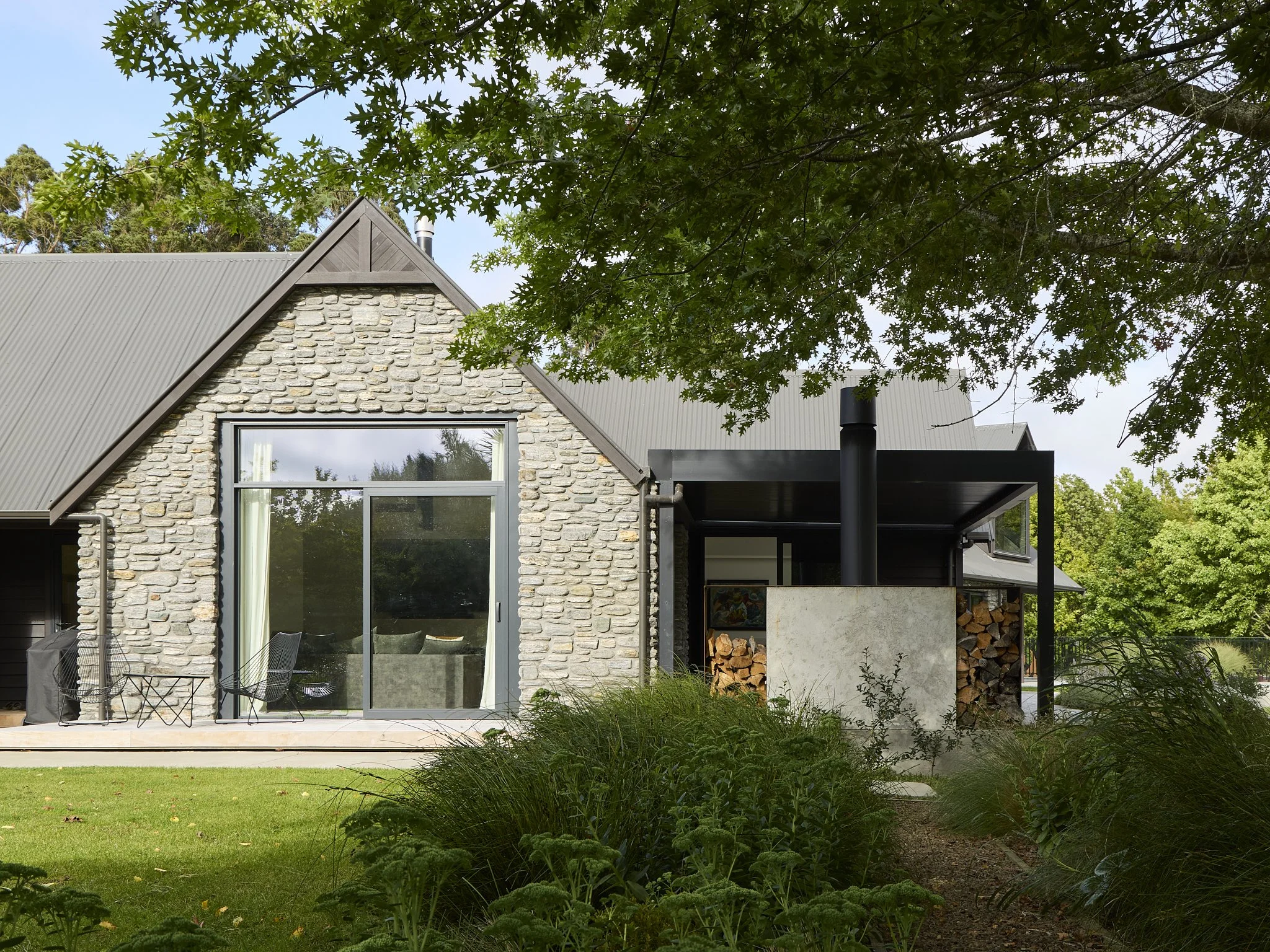 Schist-clad Tai Tapu renovation with outdoor fireplace and deck