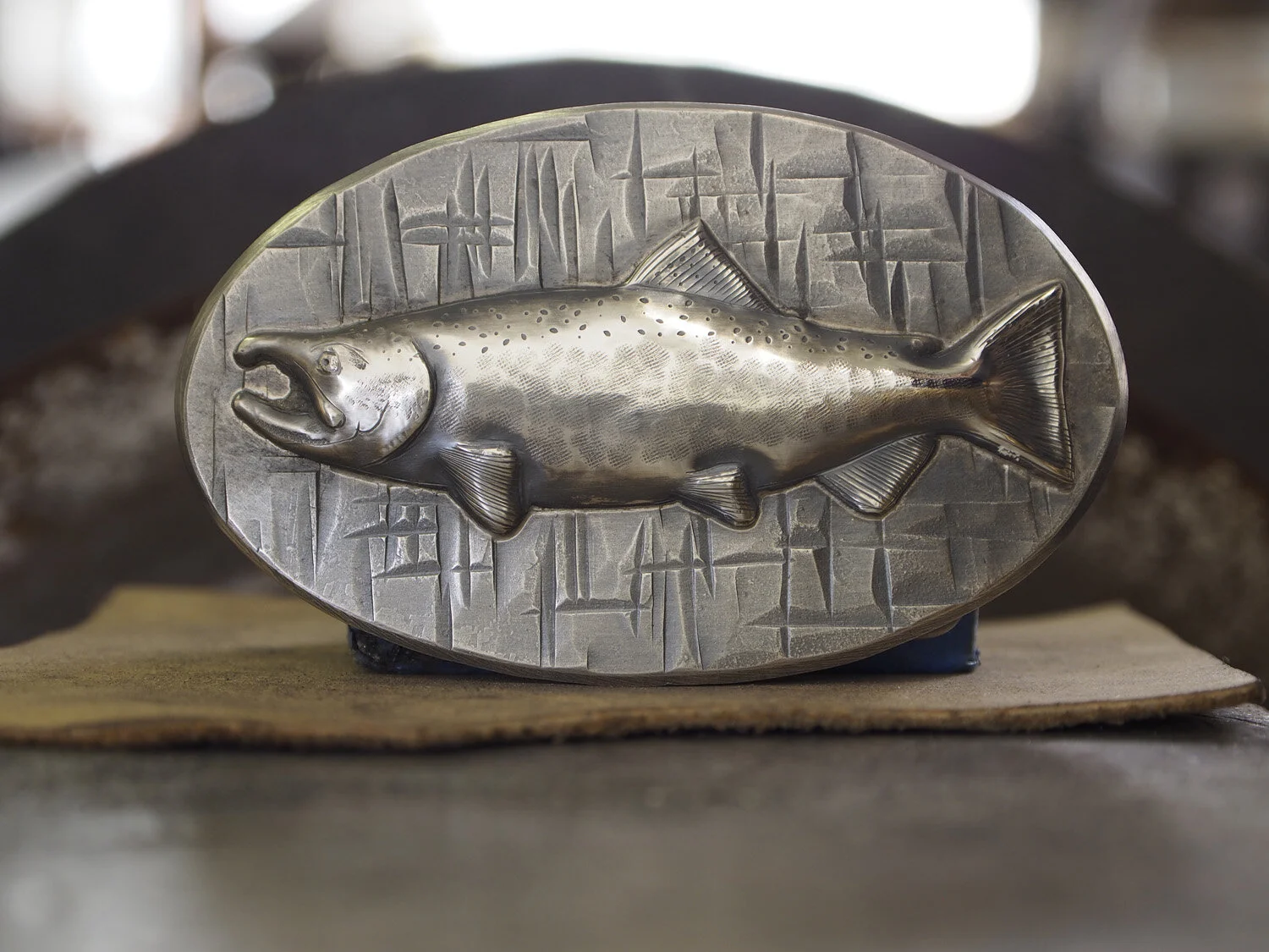 Coho salmon in sterling silver on a 3.25" wide steel belt buckle. "Sawhammer" texture.