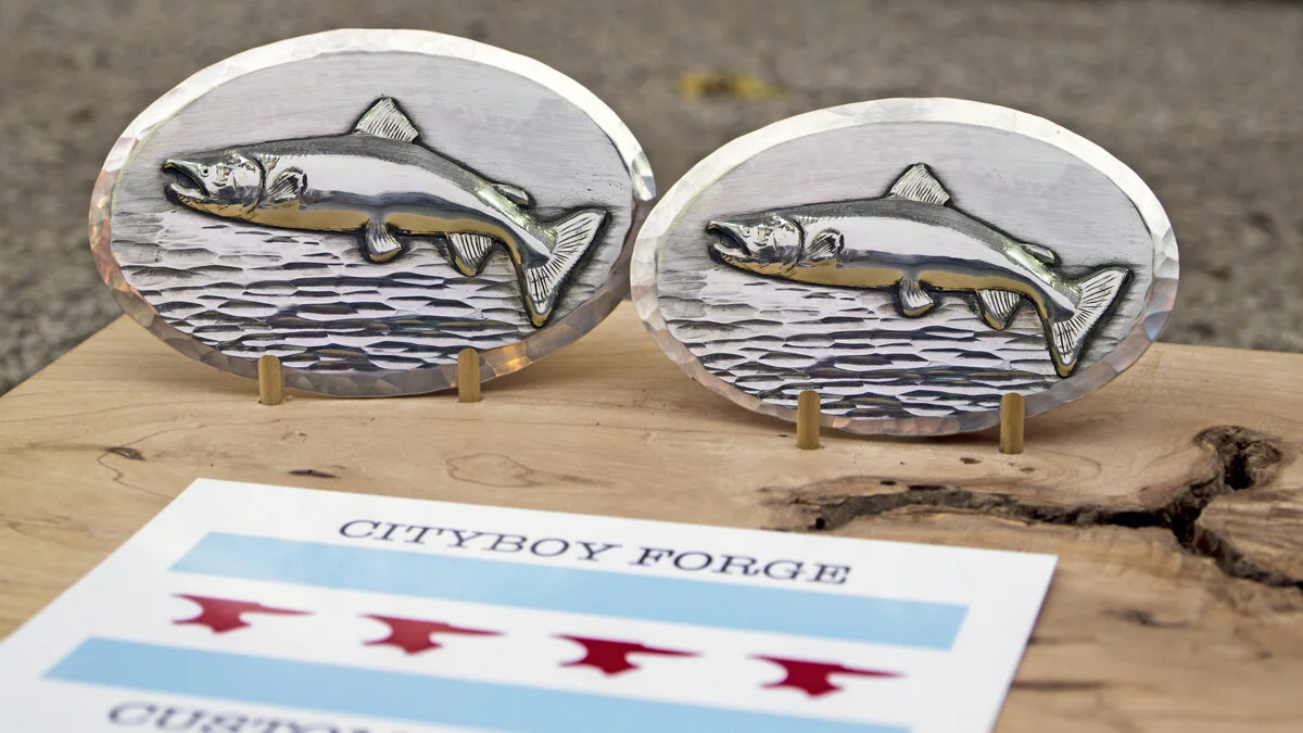 A pair of sterling silver "His and Heirs" leaping atlantic salmon belt buckles. Three point 5 and 3.25 inches wide, respectively. 