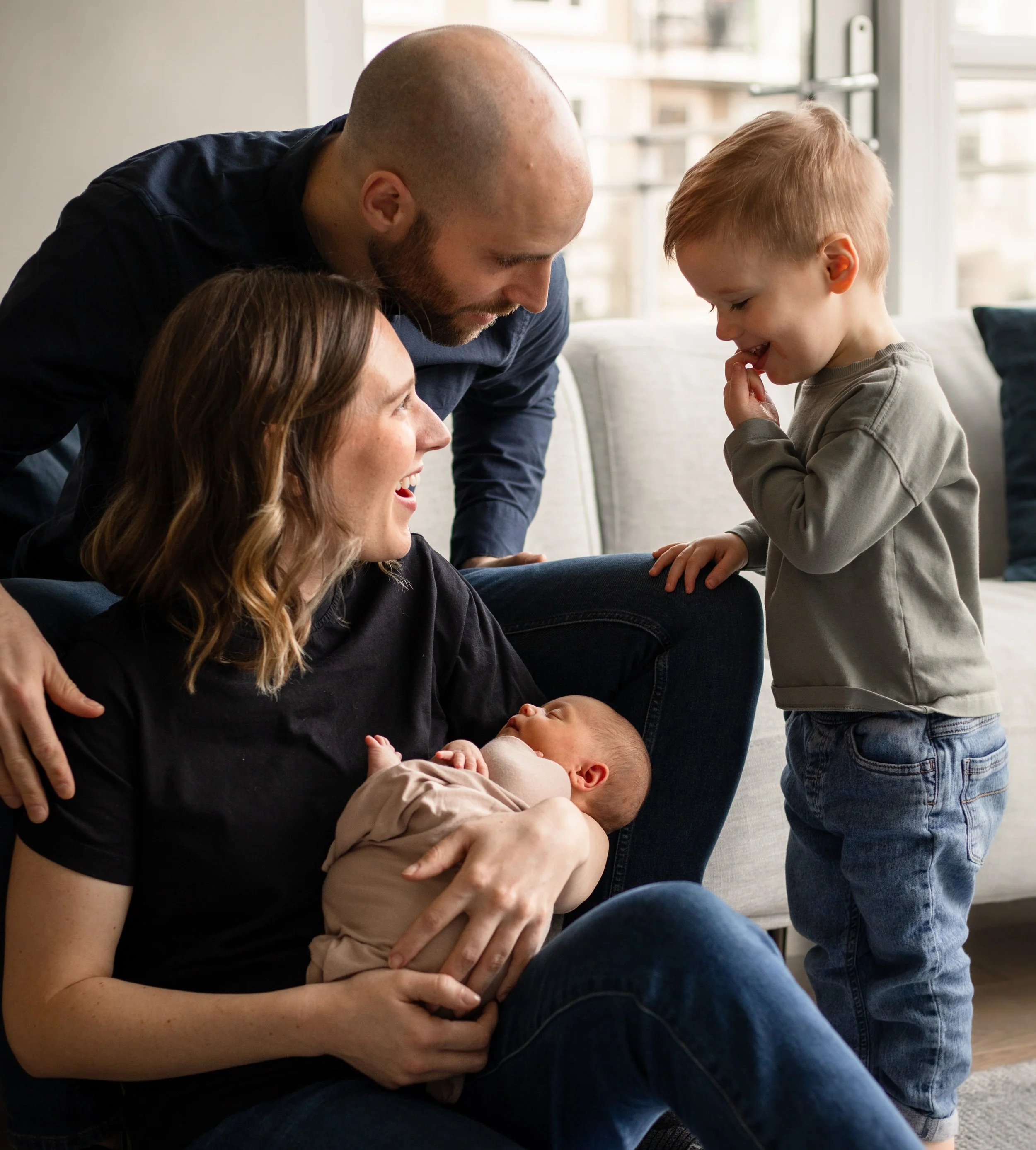 Toddler meeting newborn sibling with parents at home