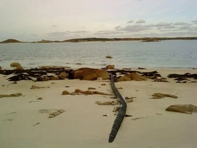 St. Martin&rsquo;s, Isles of Scilly, c.2010
Submarine cable landfall and infrastructural shoreline
photo 4x6 inches 

The photograph captures a submarine telecommunications cable as it breaches the littoral zone, moving from oceanic depth onto terres