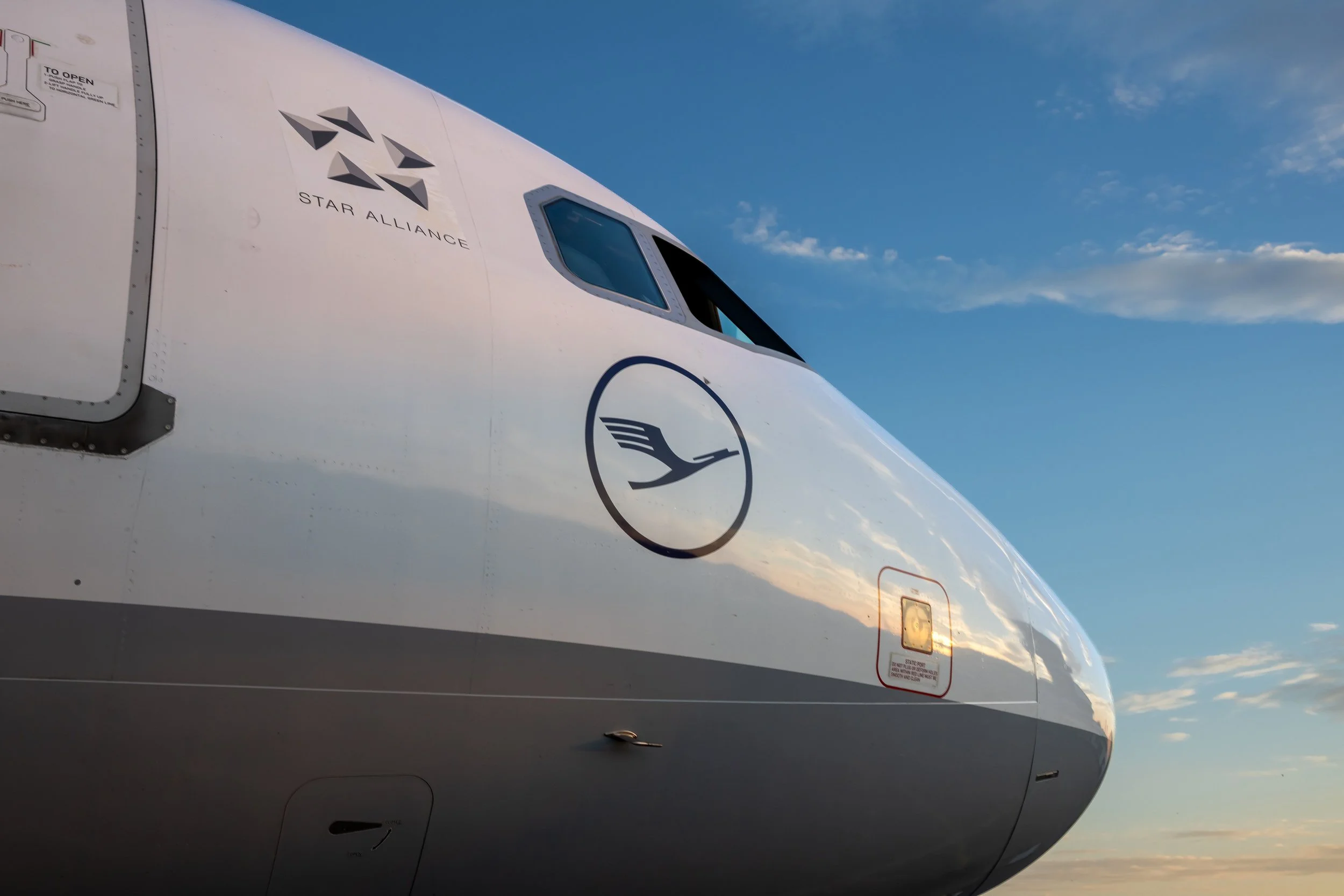 Close-up of a Lufthansa aircraft nose and cockpit against a blue sky.