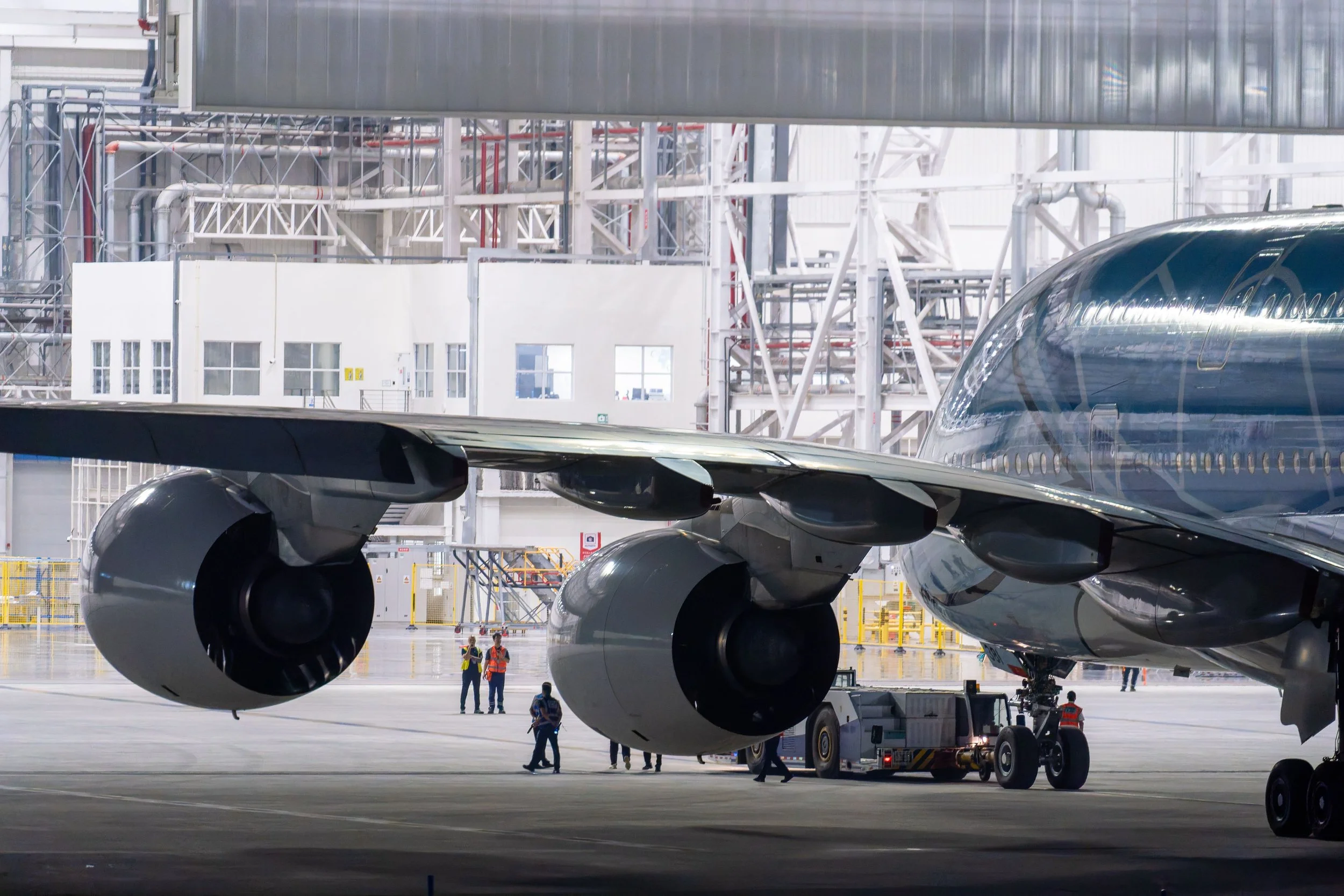 Widebody aircraft inside a maintenance hangar with engineering and ground support teams working around the aircraft.