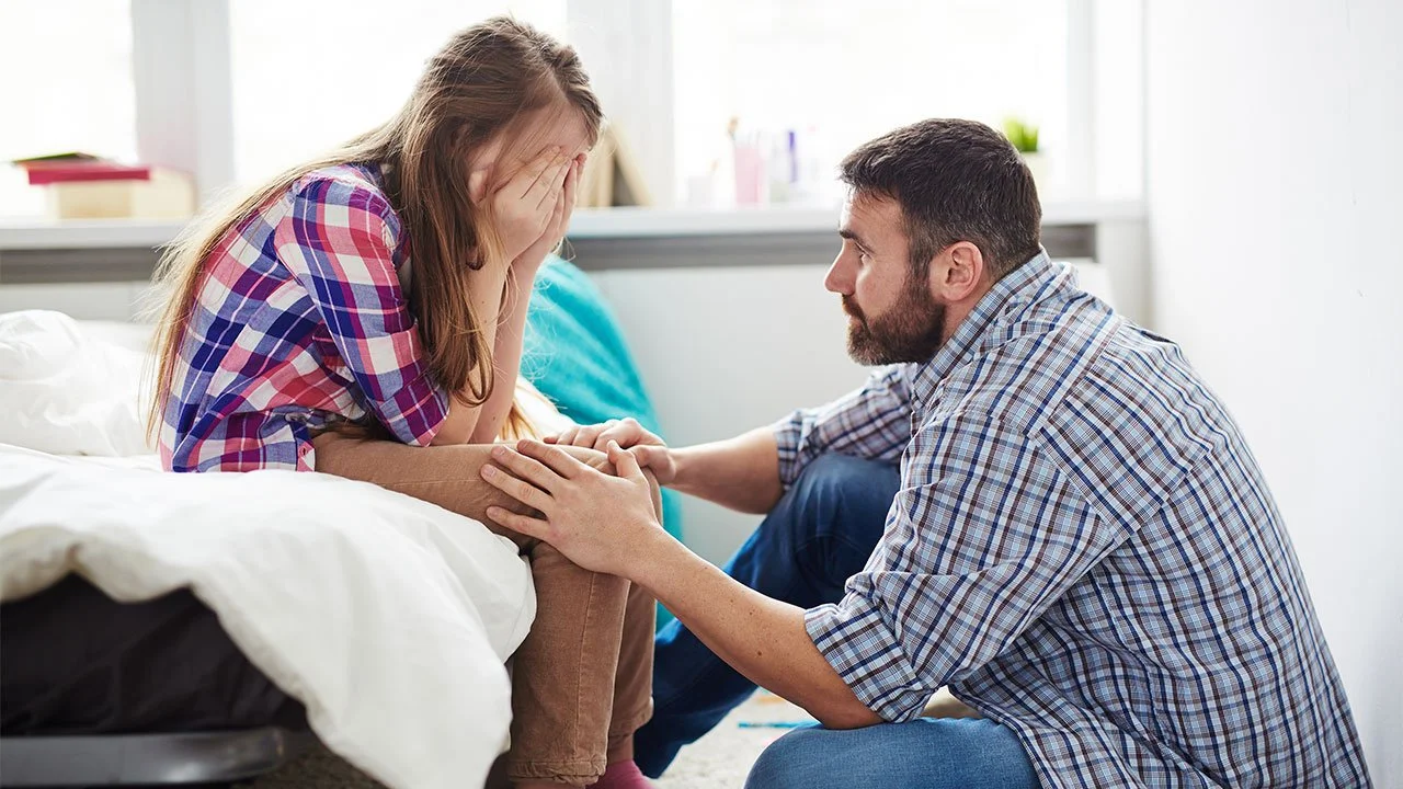 Teen girl being comforted by farther