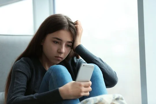 Teen girl with head in hands on her phone