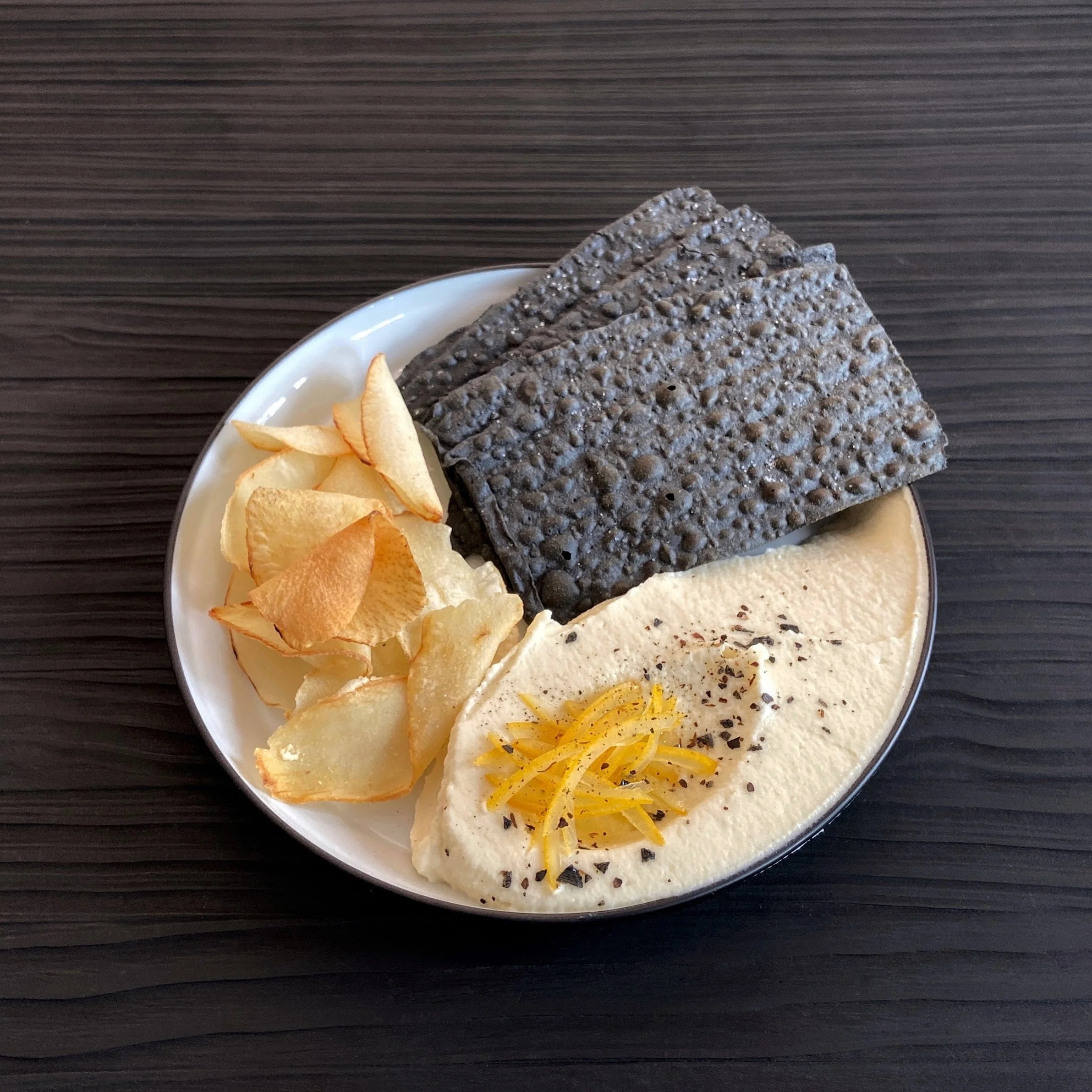 Break & Scrape de Crema de Apionabo Asado con Regaliz, Aceite de Limón, Limón Preservado, Sal de Lima Negra, Chips de Yuca y Pane Carasau Nero