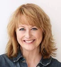 Smiling woman with blonde hair wearing a denim jacket