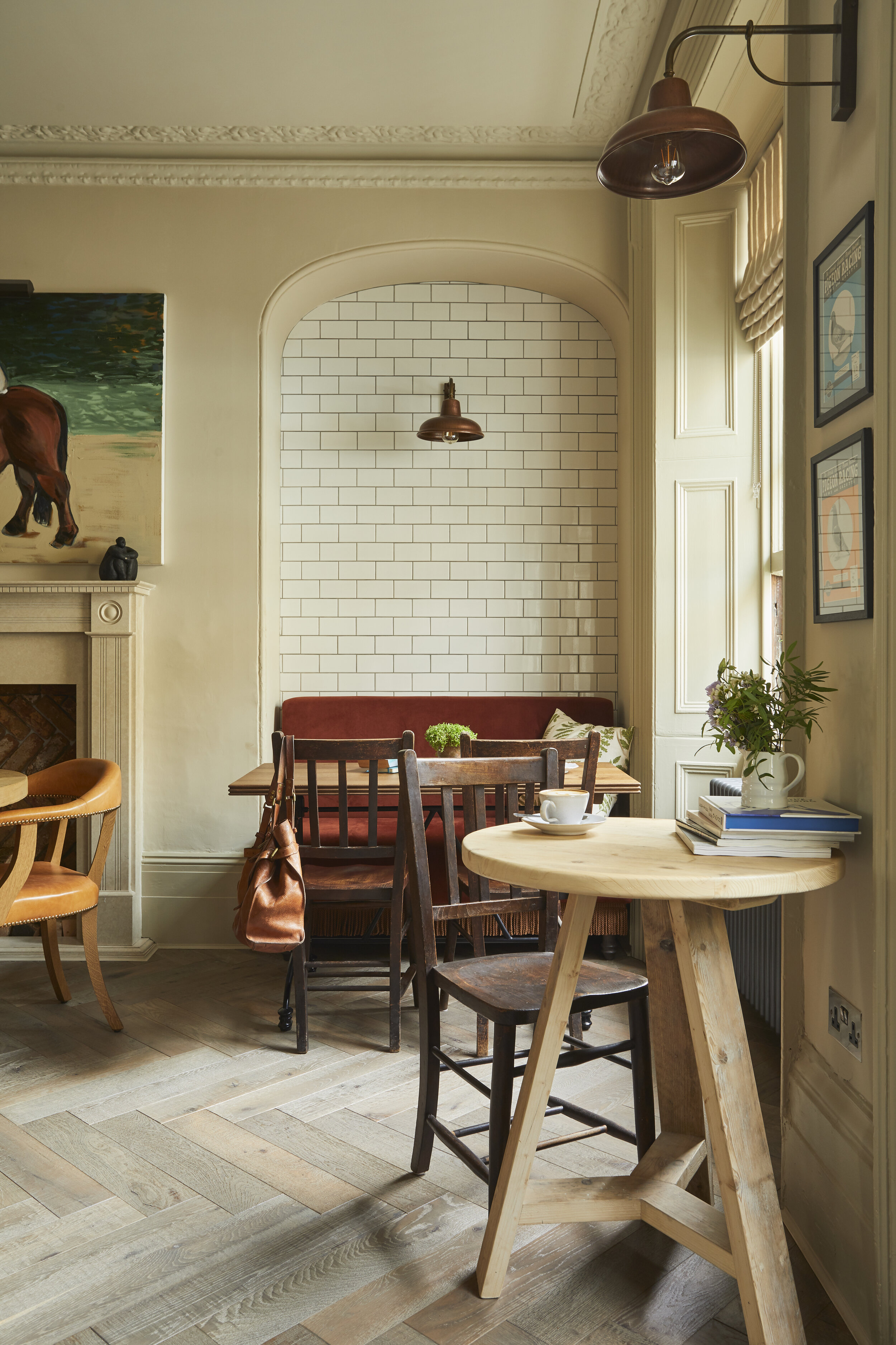 Cozy cafe corner with wooden tables and chairs, a wall with white subway tiles, and a window with beige blinds.
