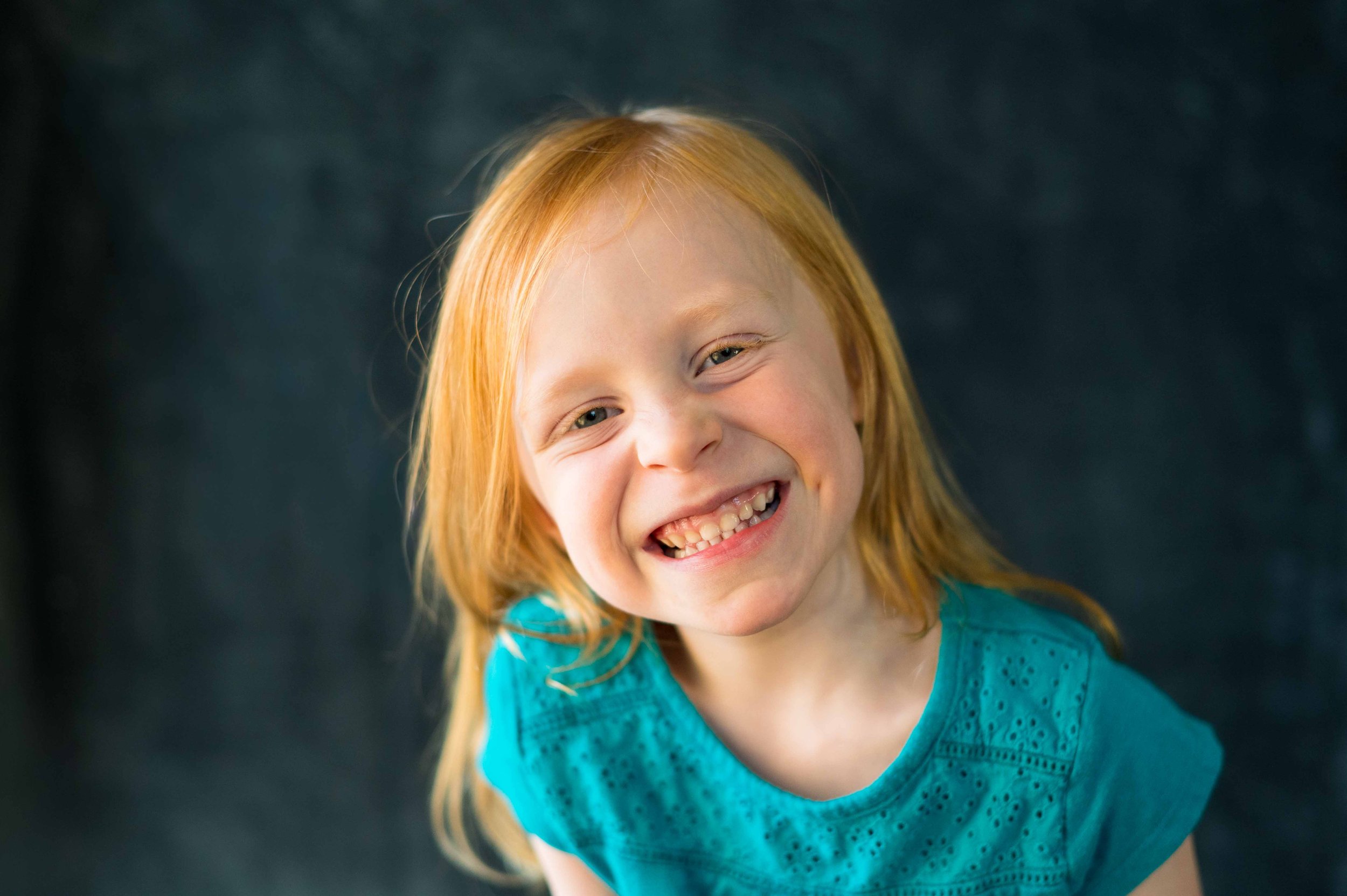 Little girl smiles at the camera for her preschool photos with the Longmont School Photographer, Sara Herkes