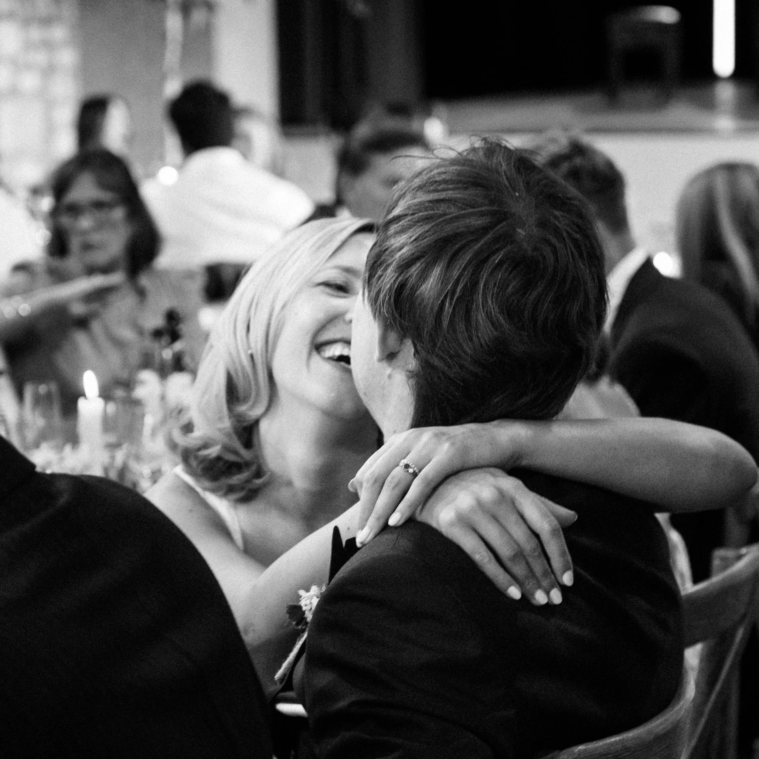 People sitting closely together, engaged in conversation at a social event, smiling and enjoying each other's company.
