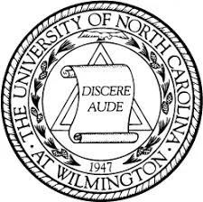 Seal or emblem of the University of North Carolina Wilmington featuring a scroll with the Latin phrase 'Disce Aude' and the year 1947.