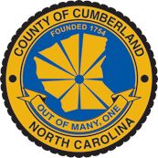 Seal of Cumberland County, North Carolina, featuring a yellow border with black text and a central blue background with a yellow graphic of the county and a banner that says 'Out of Many, One'.