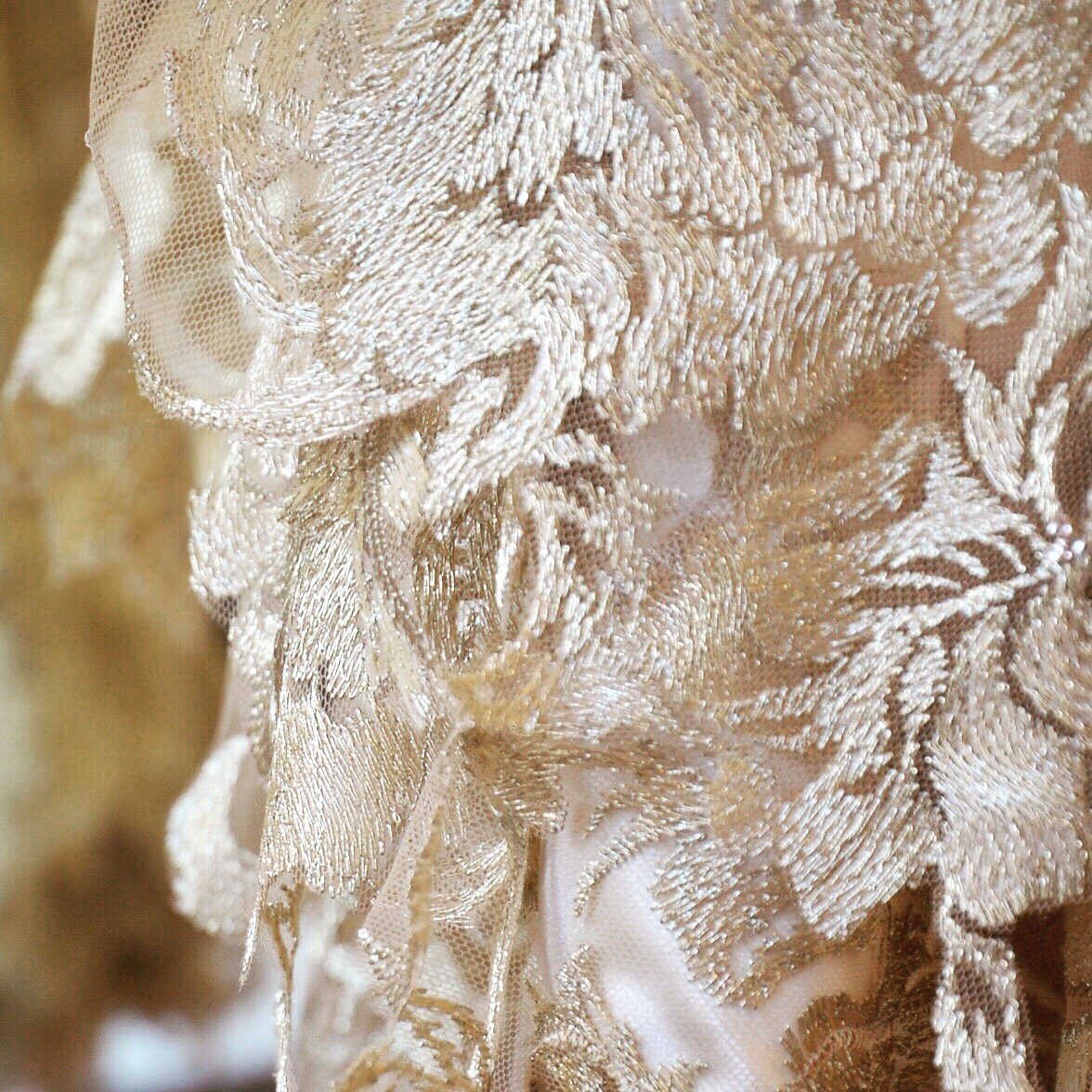 Hem detail on a gold lace couture dress
