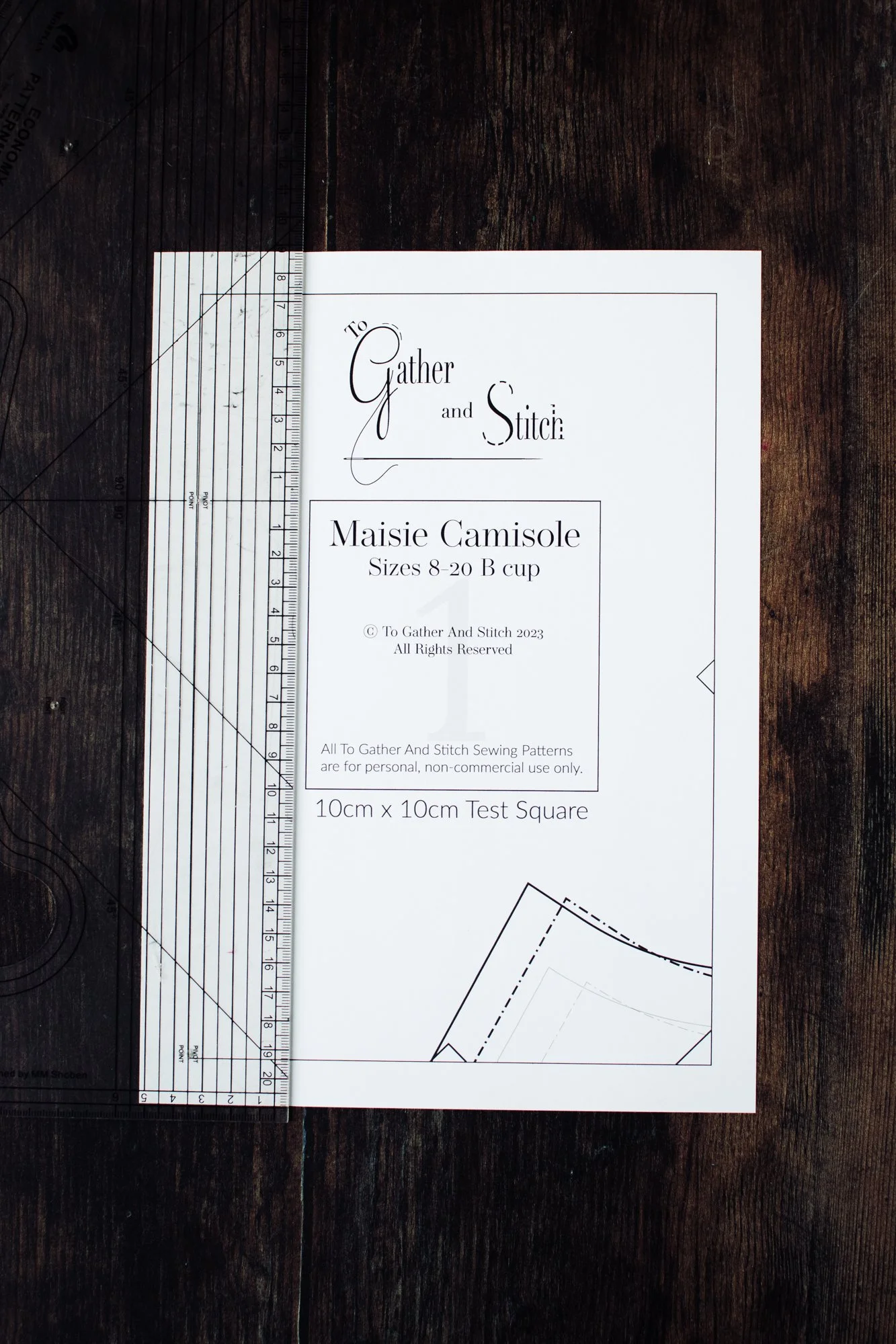 Using a ruler to check the measurements of the Test Square on a printed page of a To Gather And Stitch sewing pattern