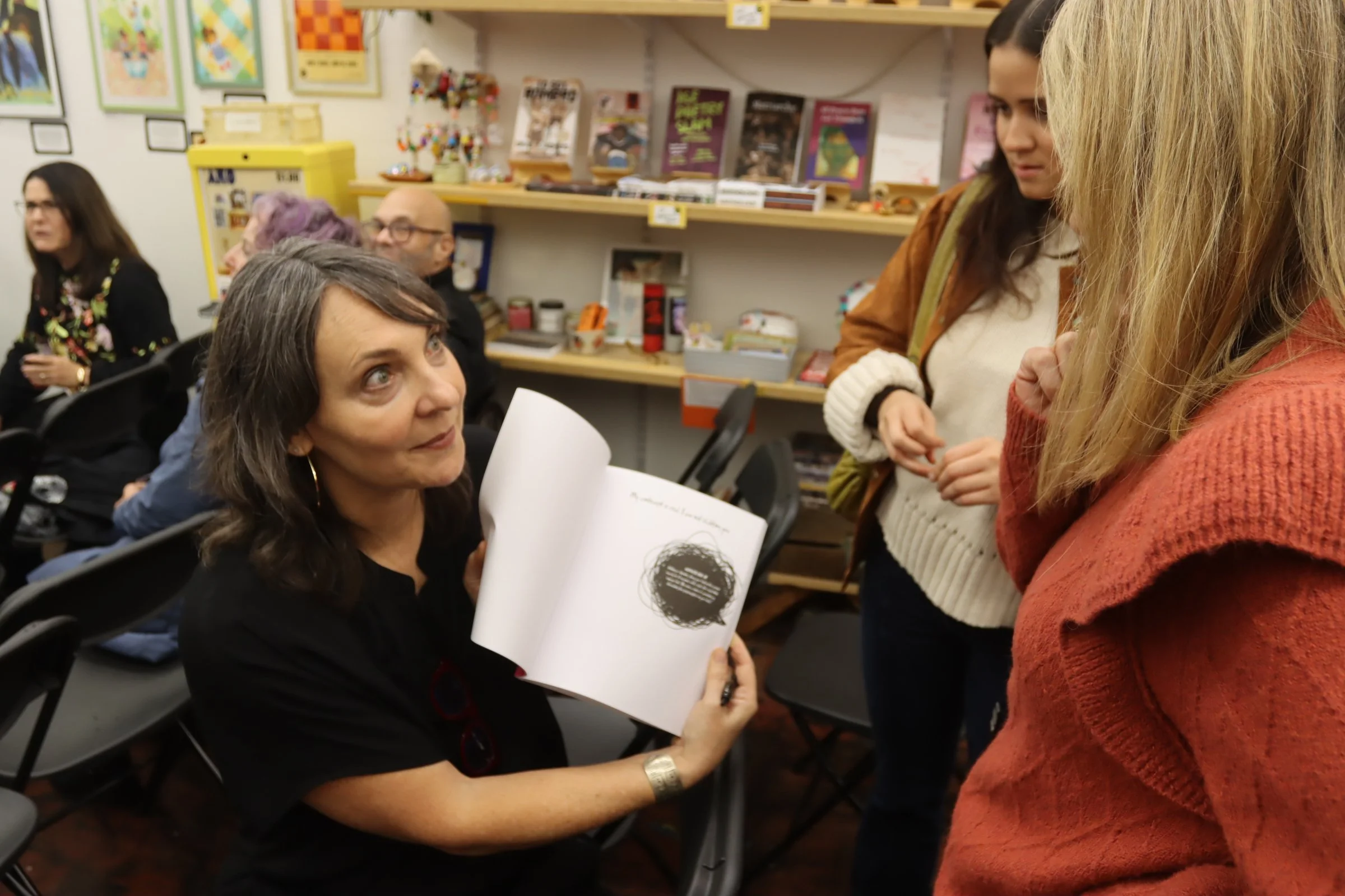 Arianne Showing inside pages of Book to people at book launch event