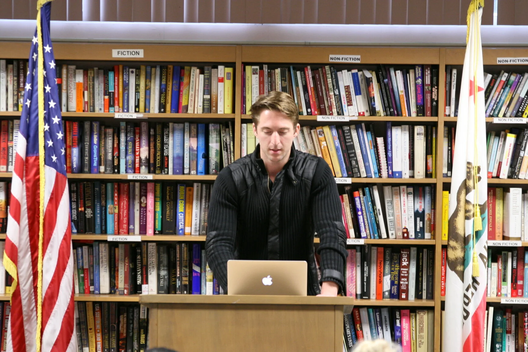 Man reading from Laptop at pedestal in library