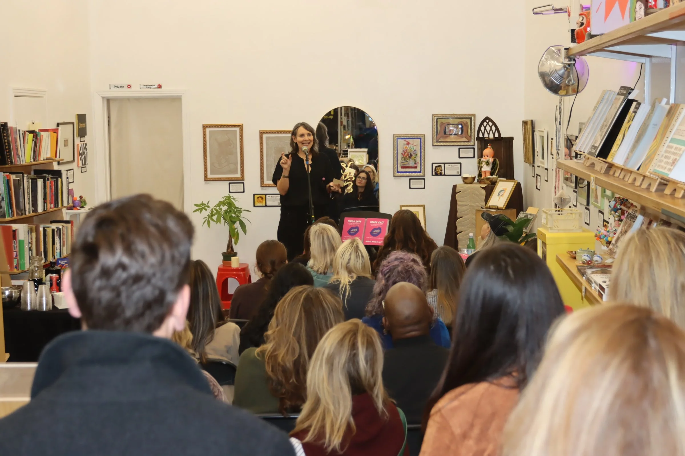 Arianne talking to Crowd at book launch shot from back of room