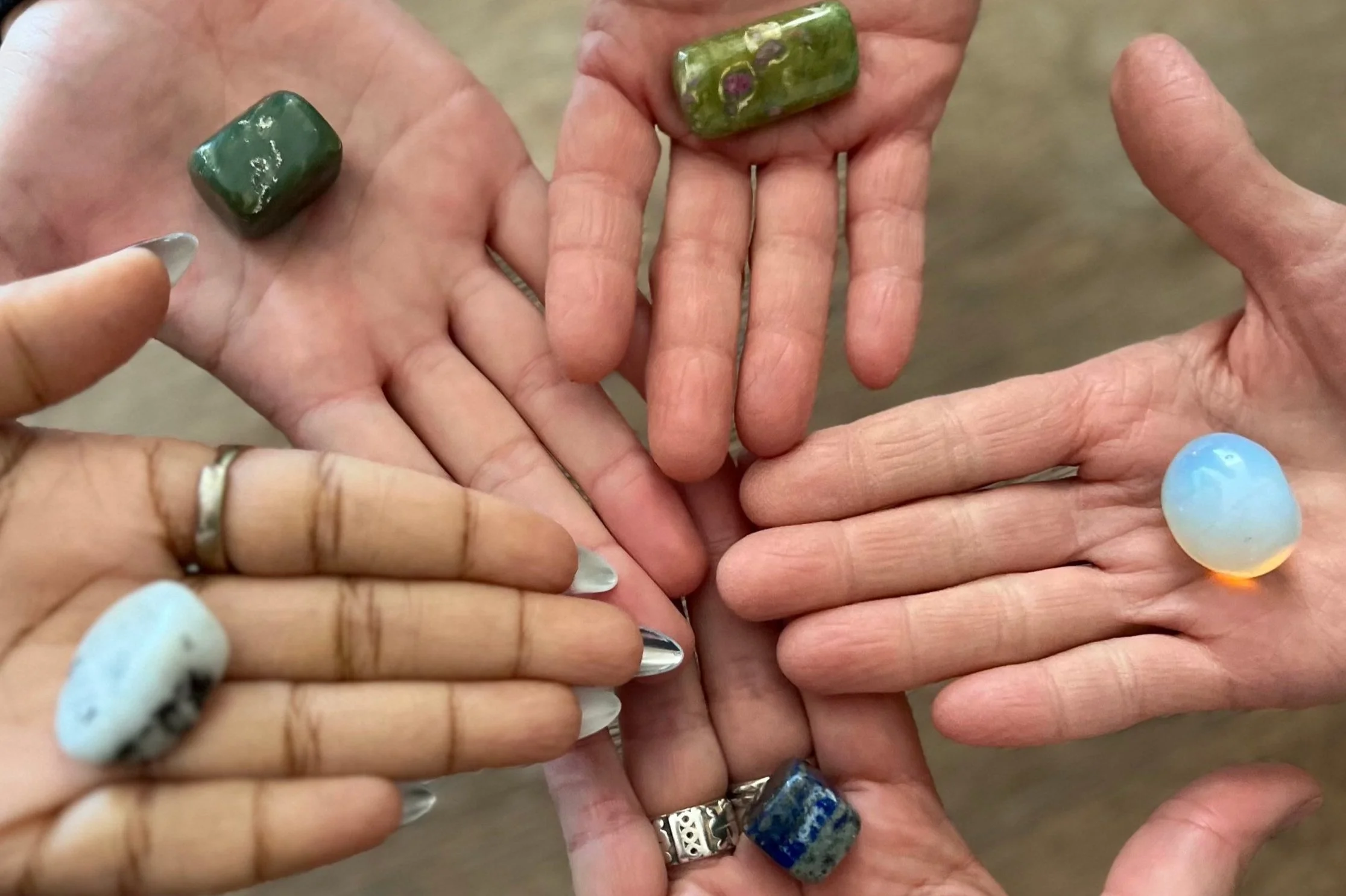 Circle of hand palms open , face up with polished stones in each palm.