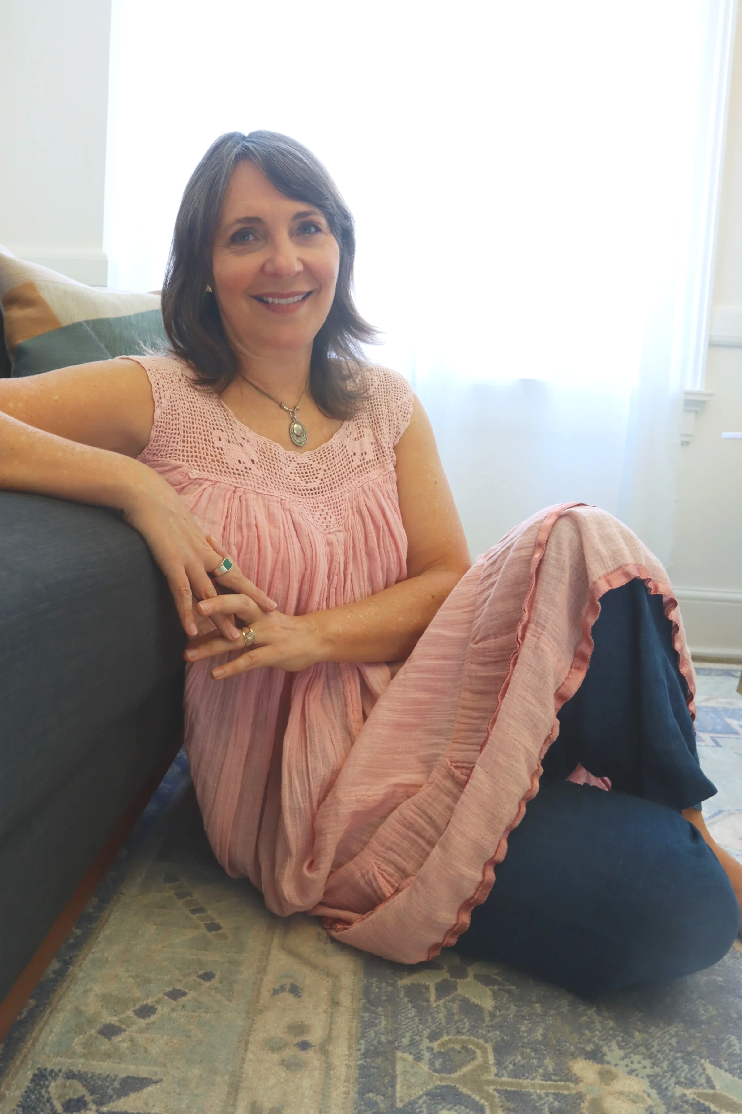 Portrait Arianne MacBean sitting on floor leaning against couch