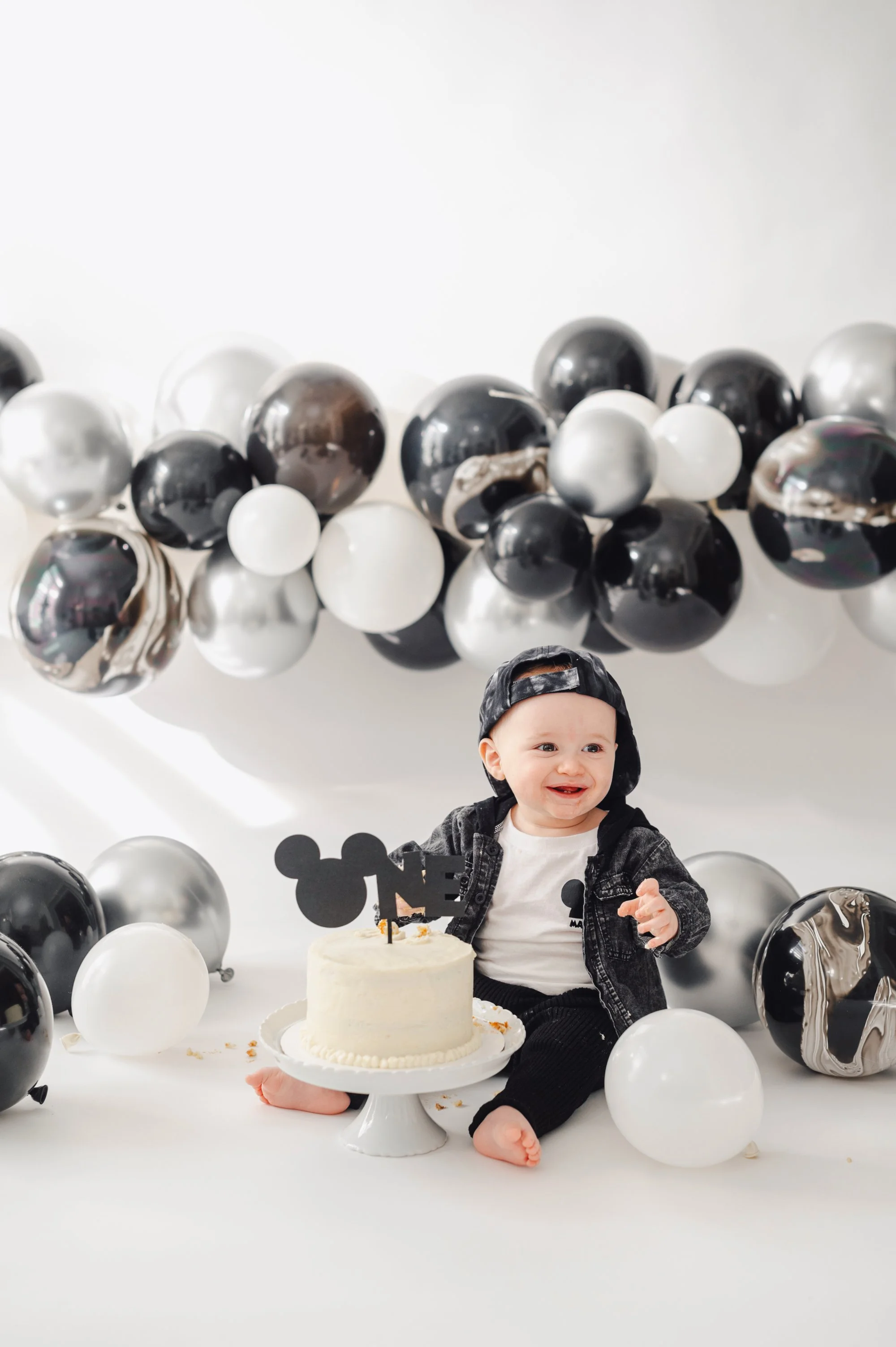 mickey mouse cake smash photography session for a one year old boy. Black and white decor on a white backdrop. Cake smash photography, Toronto cake smash photographer
