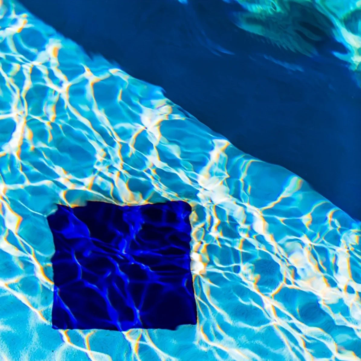 Abstract fine-art photograph of turquoise pool water and shimmering reflections, presented as a glossy face-mounted acrylic print.