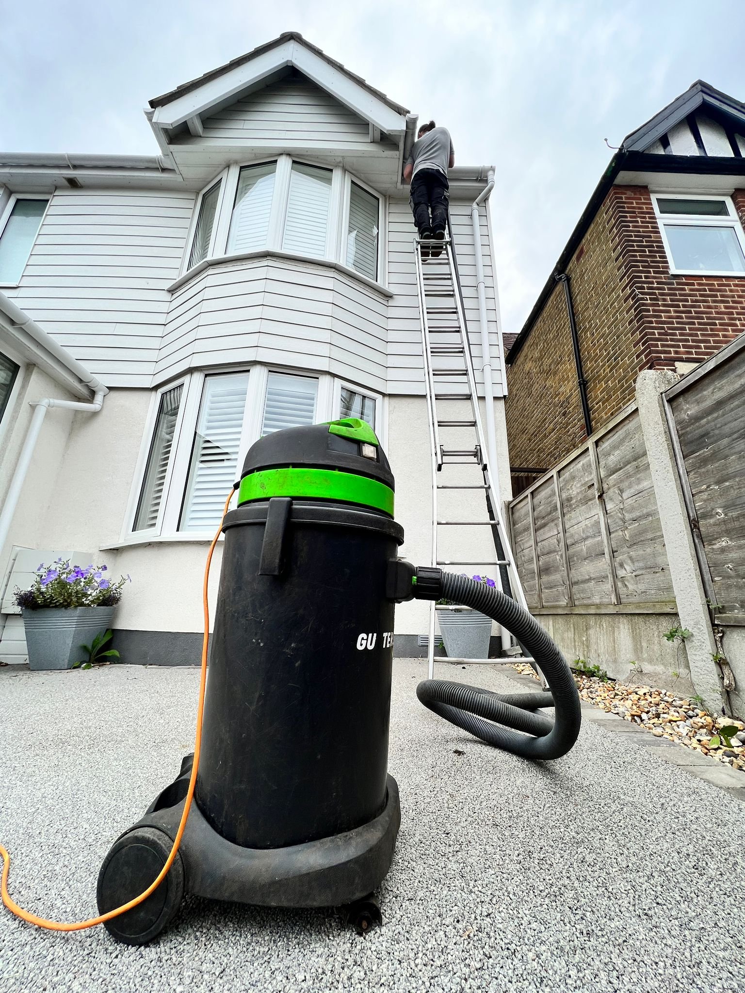 Gutter vac being used with a ladder