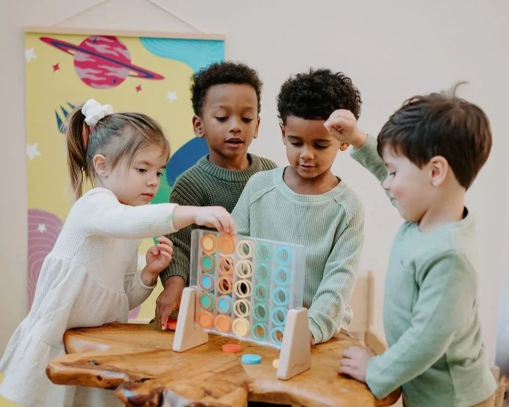 Four preschool children playing connect four at Balanced Family Academy
